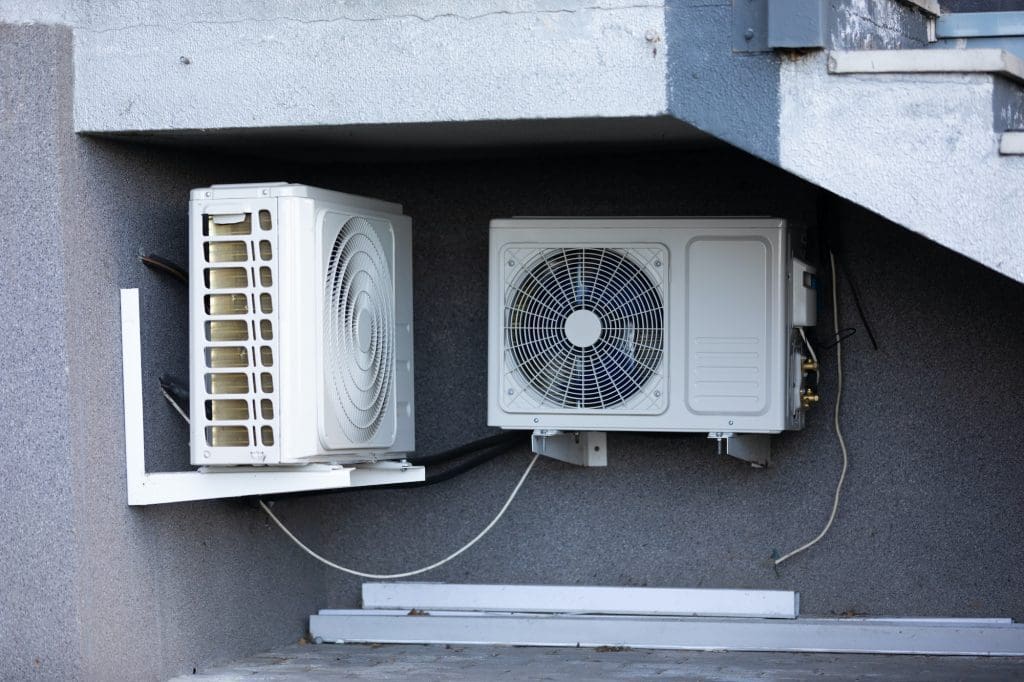 two units of outdoor air conditioners for heat dissipation are hung on the wall outside the building